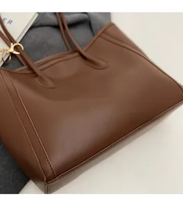 Detailed view of dark brown leather tote bag with fine stitching and slim shoulder straps
