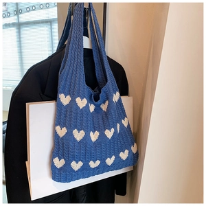 Détail macro du cabas en tricot bleu avec motifs de cœurs blancs en jacquard doux