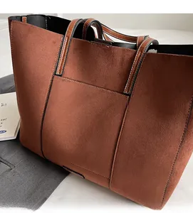 Detail of a large brown matte tote bag featuring contrast black trim and visible stitching