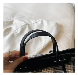 Detail of durable black leather handle and vintage plaid pattern on a large tote bag