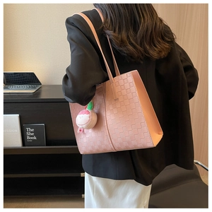 Pink tote bag detail with woven texture and a cute cartoon plush pendant for daily use