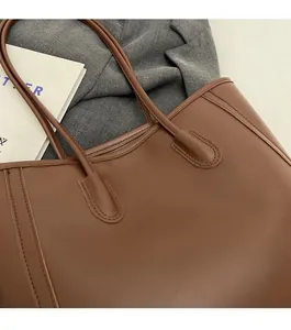 Close-up of reinforced shoulder strap stitching on brown leather tote bag detail