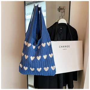 Détail du sac fourre-tout en tricot bleu avec motif cœur blanc et bandoulière large
