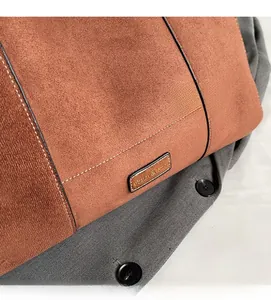 Detail of brown faux suede tote bag featuring white contrast stitching and metal logo plate