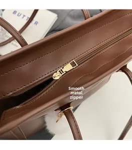 Detail of smooth gold zipper hardware and brown leather texture on large tote bag