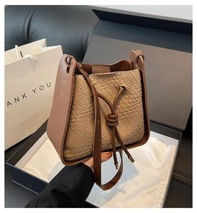 Brown woven bucket bag with drawstring closure and matching gift box and shopping bag