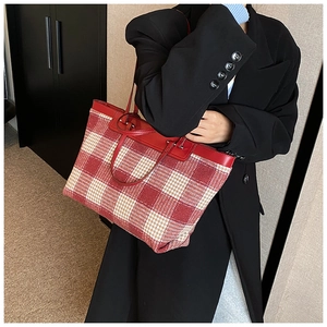 Detail of red and white plaid tote bag featuring leather handles and tweed texture