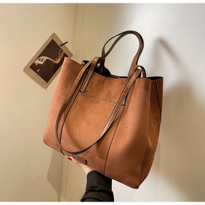 Detail of caramel brown tote bag showing matte faux suede texture and leather brand patch