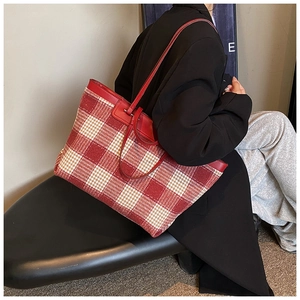 Detail of red and cream plaid canvas tote bag with premium leather handles and trim