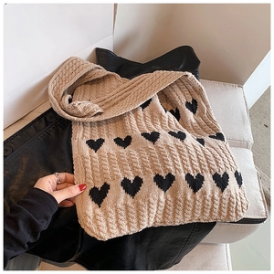 Détail du tissage et motif cœur noir sur le sac cabas en maille beige pour femme