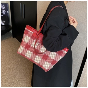 Detailed side view of large red and beige plaid canvas tote bag with leather straps