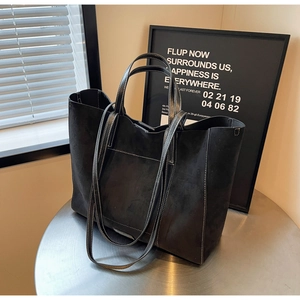 Detail of black matte tote bag featuring contrast white stitching and front pocket