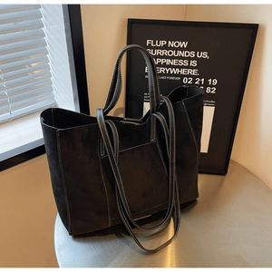 Detail of black suede tote bag featuring white contrast stitching and long handles