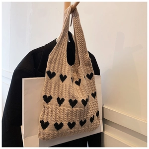 Gros plan du sac cabas en tricot beige avec motifs de cœurs noirs et torsades