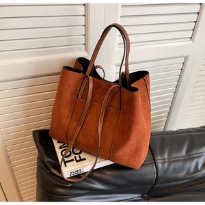 Close-up of brown suede tote bag with fine stitching on a vintage designer book