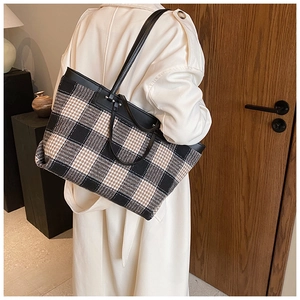 Detail of plaid tote bag featuring checkered tweed fabric and black leather strap