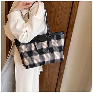 Detailed view of the plaid tote bag showing its textured tweed fabric and leather handles