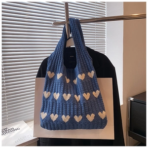 Détail du sac cabas en tricot bleu avec motifs de cœurs blancs et maille torsadée