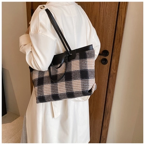 Detail of checkered tote bag with black leather trim and long shoulder straps