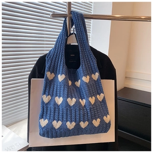 Détail du sac cabas en tricot bleu avec motifs de cœurs blancs et texture douce