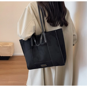 Detail of black large tote bag featuring white contrast stitching and dual strap design