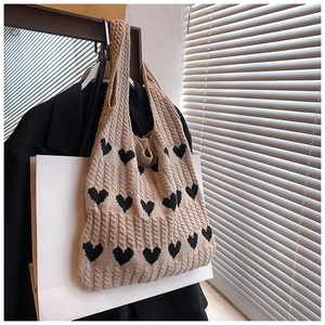 Gros plan sur un sac cabas en coton beige à motifs de cœurs noirs tricotés en jacquard