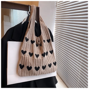 Détail d'un cabas en maille avec motifs cœurs noirs et texture torsadée