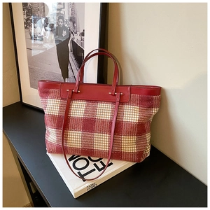 Detail of red houndstooth tote bag featuring premium leather handles and dual straps