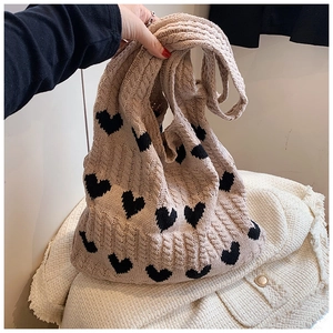Détail du sac cabas en tricot beige avec motifs de cœurs noirs et texture torsadée