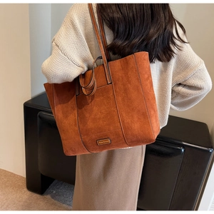 Close-up of caramel suede tote bag featuring detailed matte texture and metallic logo plate