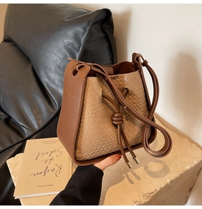 Detail of vintage brown bucket bag with woven texture and adjustable strap on stone base