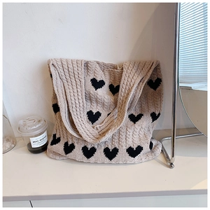 Détail du sac cabas en maille avec motif de cœur et texture torsadée en beige