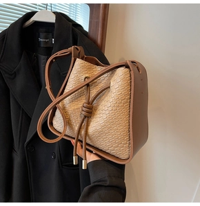 Detail of a two-tone bucket bag featuring woven texture and brown leather drawstring