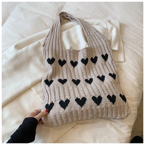 Détail du sac cabas en maille beige avec motifs cœurs noirs et texture en coton doux
