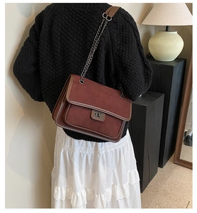 Close-up of diamond quilted pattern and vintage metal twist lock on a burgundy shoulder bag