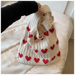 Gros plan du motif cœur sur le sac en maille montrant la texture douce du coton
