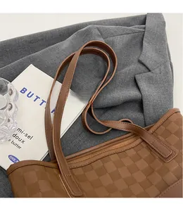 Detail of brown checkered embossed tote bag with adjustable strap and smooth zipper