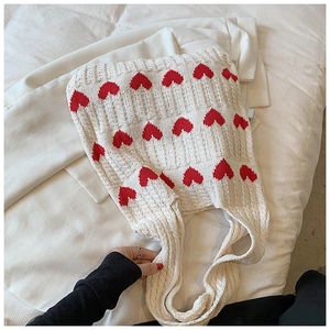 Détail macro du sac cabas en maille crème douce avec des motifs de cœurs rouges tissés