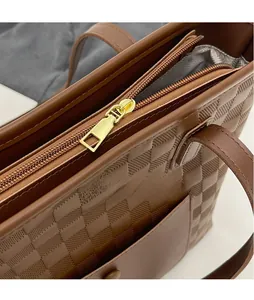 Detail view of smooth gold zipper and herringbone fabric lining on brown tote bag