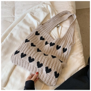 Détail du cabas en tricot beige à motifs de cœurs noirs et texture épaisse en maille