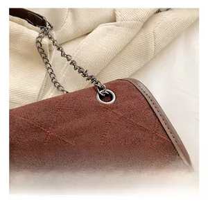 Detail of brown quilted suede bag showing dark grey metal eyelets and fine chain strap