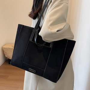 Large black matte suede tote bag with white contrast stitching and long shoulder straps