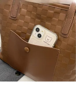 Detail of checkered tote bag with brown embossed texture and a front pocket for storage