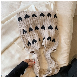 Gros plan du sac cabas en tricot beige avec motifs de cœurs noirs et texture côtelée douce