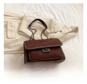 Detailed shot of dark brown quilted suede shoulder bag with metal twist lock and chain strap