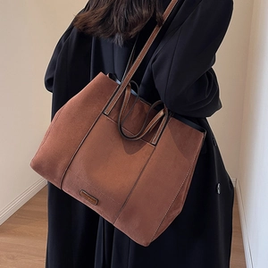 Large brown matte suede tote bag with shoulder straps worn by model for daily commute