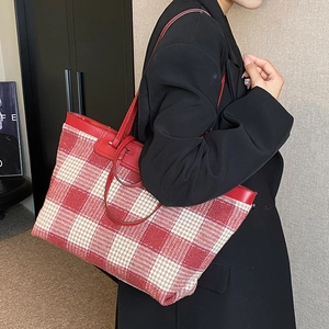 Large red and white checkered canvas tote bag with leather straps on model's shoulder