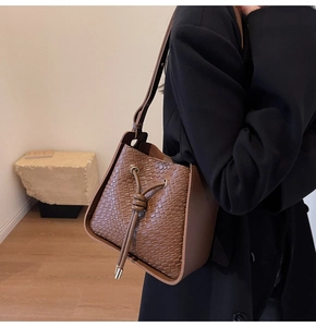 Detail of brown vintage bucket bag with crocodile embossing and U-shaped frame