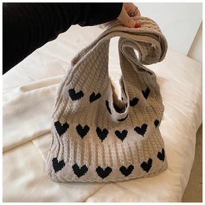 Gros plan du motif cœur tricoté sur un sac cabas beige en coton doux et texturé