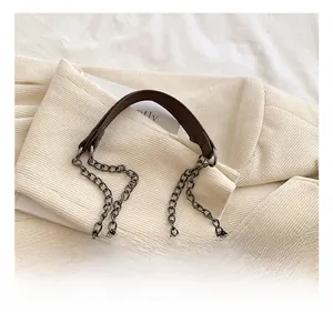 Close-up of deep brown quilted bag featuring bronze chain strap and leather top handle